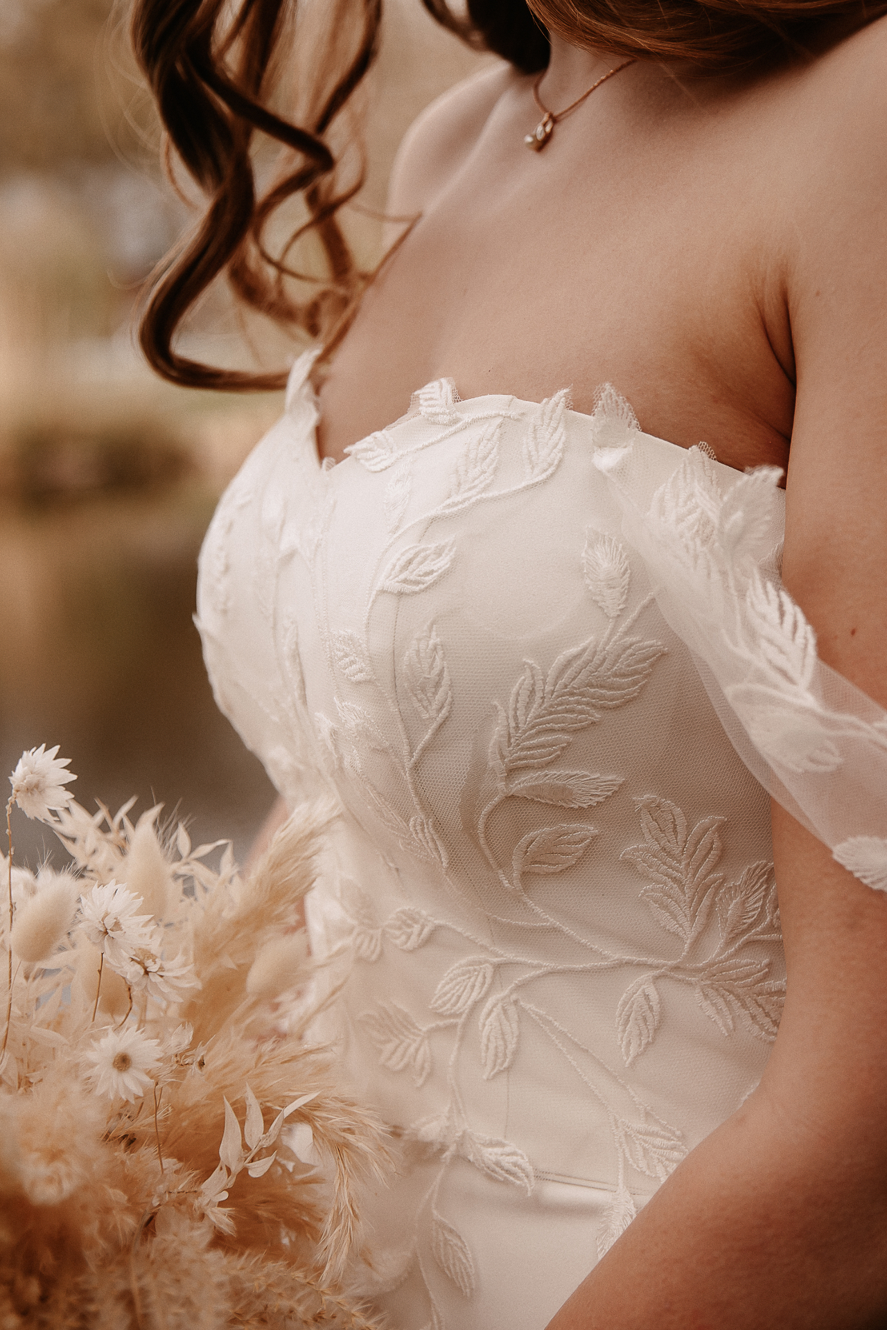 Braut in einem fließenden, eleganten Brautkleid mit zarter Blattspitze